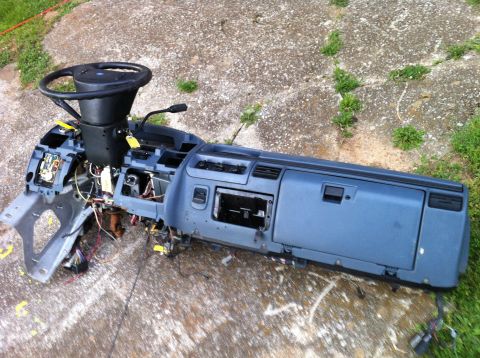 1992 Ford Bronco - The dashboard assembly, including the steering wheel and exposed wiring, is laid out on a concrete surface.