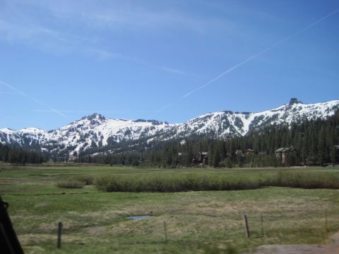1989 Ford Bronco - A scenic view of snow-covered mountains and a lush green valley, dotted with trees and buildings.