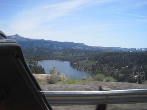 1989 Ford Bronco - View from inside a vehicle shows a scenic landscape with a lake and forested mountains under a blue sky.