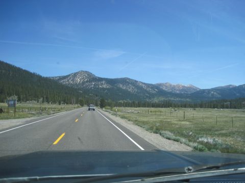 1989 Ford Bronco - View from a vehicle driving on a highway towards mountains under a clear blue sky.
