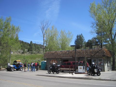 1989 Ford Bronco - A group of people and several vehicles are gathered at a rural gas station on a sunny day.