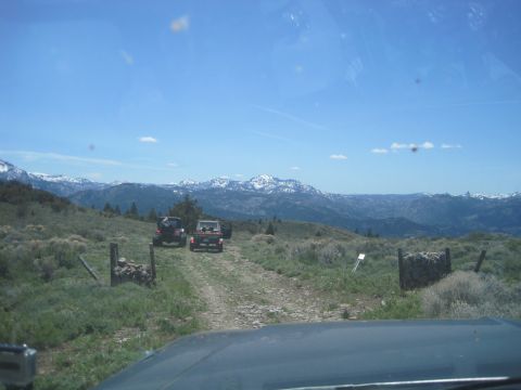 1989 Ford Bronco - Two SUVs travel on a dirt road through a scenic mountain landscape on a sunny day.