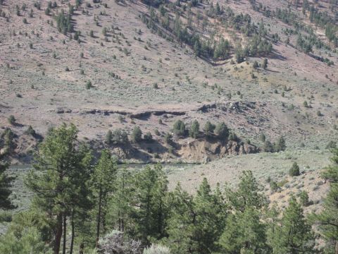 1989 Ford Bronco - A wide view of a , natural landscape a winding river and scattered pine trees on a dry, mountainous terrain.