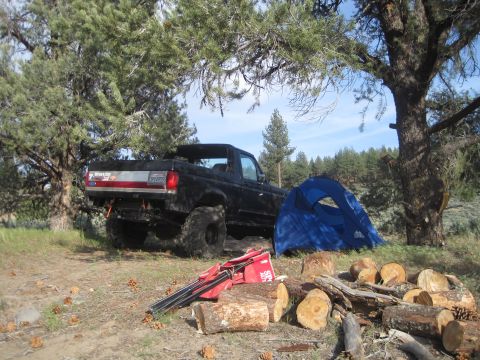 1989 Ford Bronco - Camping scene with a 1989 Ford Bronco, a tent, and cut logs for a campfire.
