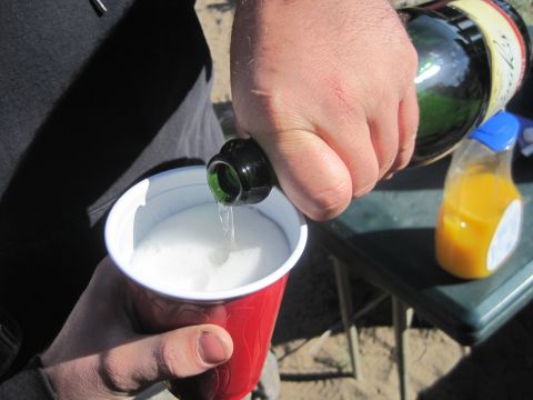 1989 Ford Bronco - A person pours a beverage from a bottle into a red cup, with a bottle of orange juice visible on a table.