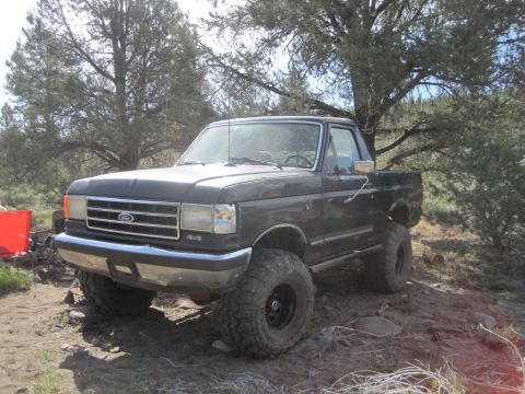 1989 Ford Bronco - This lifted 1989 Ford F-Series truck features a 4x4 badge and aggressive off-road tires, suggesting it's ready for challenging terrain.