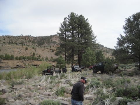 1989 Ford Bronco - A group of off-road vehicles are gathered in a scenic, landscape near a body of water.