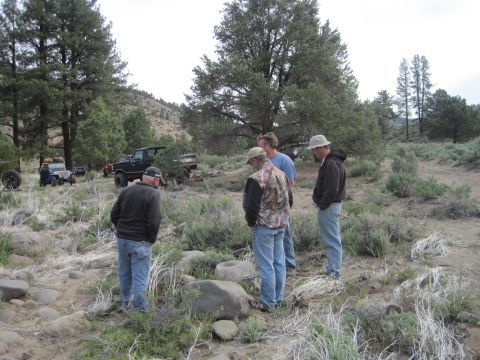 1989 Ford Bronco - Several men gather around a black Ford Bronco in a dry, brush-filled landscape.