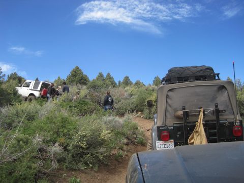 1989 Ford Bronco - A group of off-road vehicles navigate a trail through a dry, brushy landscape on a sunny day.