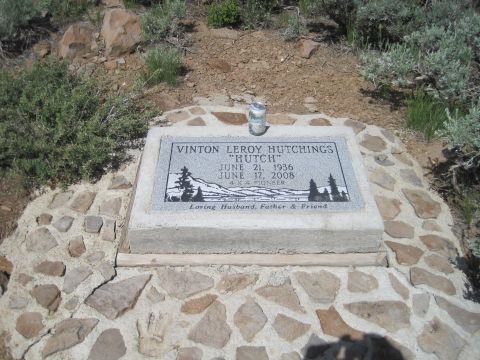 1989 Ford Bronco - A gravestone with engraved text and a landscape scene is surrounded by stones and natural vegetation.