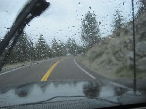 1989 Ford Bronco - Driving through a landscape with rain falling on the windshield, obscuring the view of the road ahead.