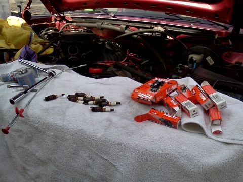 1995 Ford Bronco - Tools and new spark plugs are ready for an engine tune-up in the vehicle's engine bay.
