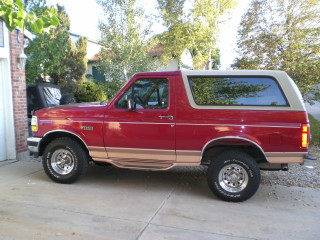 1995 Ford Bronco - Side view of a red 1995 Ford Bronco with tan accents and a removable top.