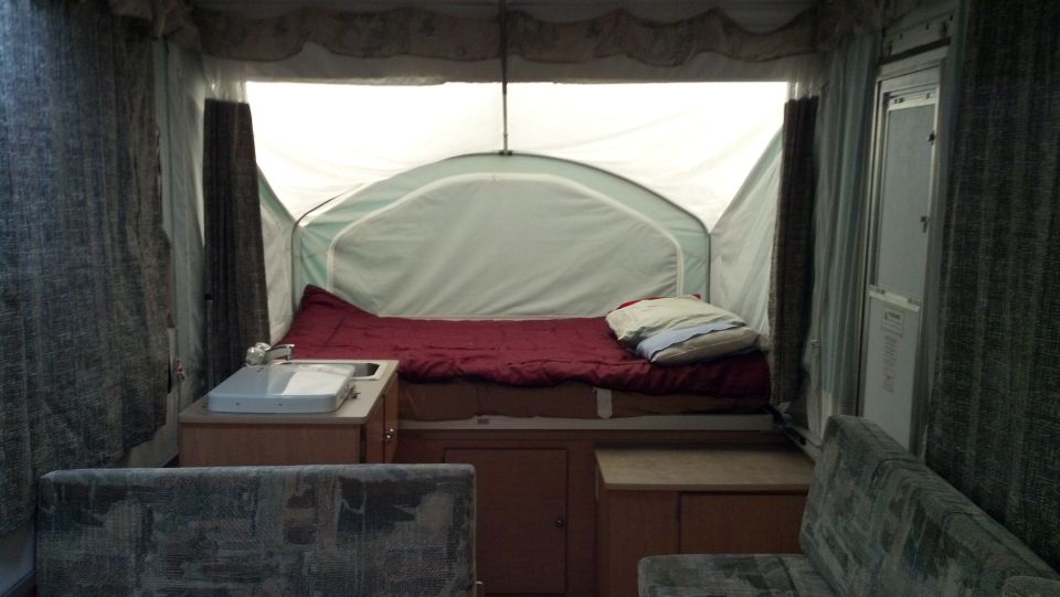 Interior view of pop-up camper with bed, sink, and seating areas