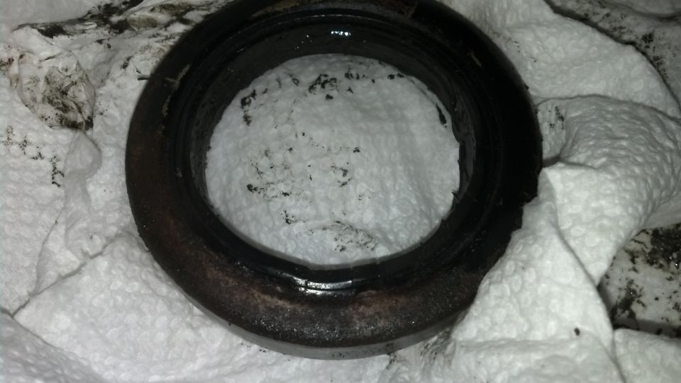 Close-up of a used, dirty oil seal resting on paper towels