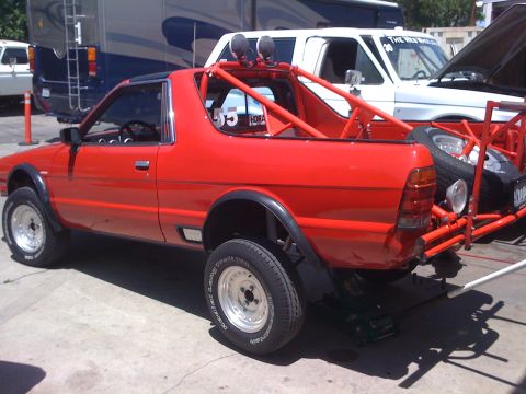 1968 Ford Mustang - Custom red pickup truck with a roll cage and off-road tires is parked outdoors.