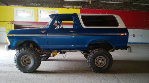 1979 Ford Bronco - Side view of a lifted blue 1979 Ford Bronco with a white removable top.