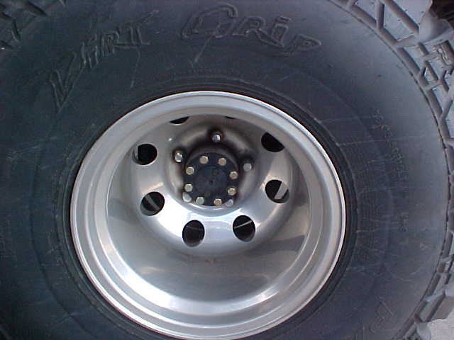 Close-up of a tire with 'Dirt Grip' text and a silver wheel with 5 lug nuts
