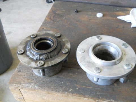 1992 Ford Bronco - Two wheel hubs are shown on a workbench, one showing signs of wear and welding, the other appearing new.
