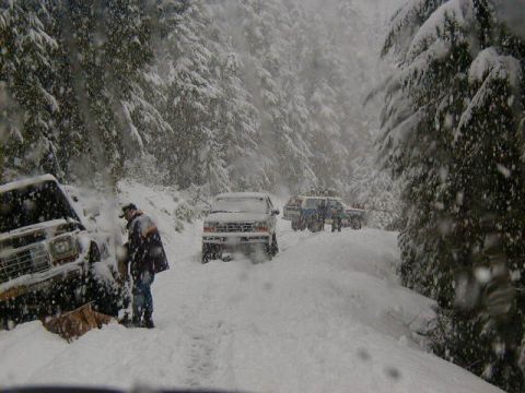 1994 Ford Explorer - Multiple vehicles navigate a snowy mountain road during a blizzard.