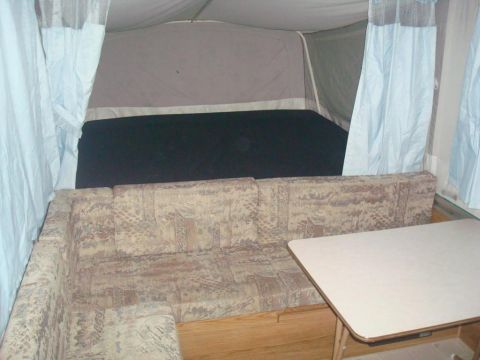 2007 Mazda 6 - The interior of a pop-up camper shows a sofa, table, and sleeping area.