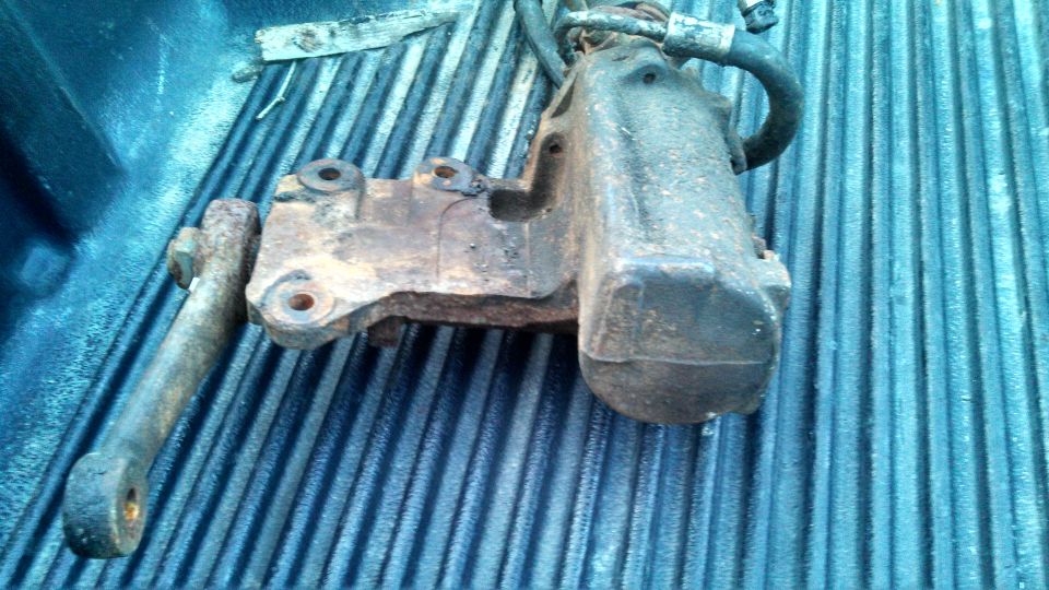 Rusty power steering gearbox with a hose attached, resting in a truck bed