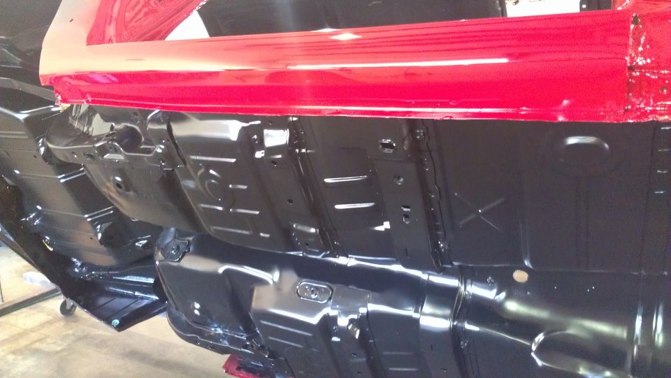 Underside of a car with red body panels and black undercarriage