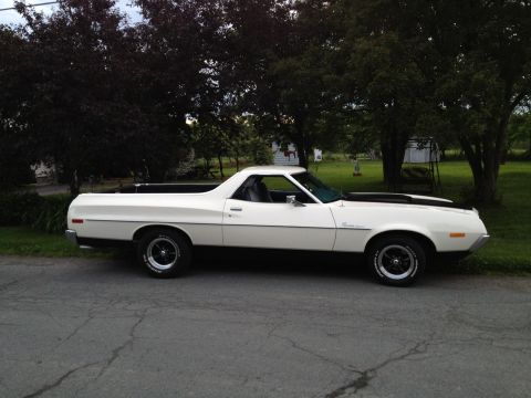 1972 Ford Ranchero - A white 1972 Ford Ranchero pickup truck is shown from the side, parked on a street with trees in the background.