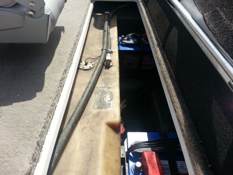 2003 Tracker Tournament - A view inside a boat reveals a fuel tank and hose, alongside two blue marine batteries.