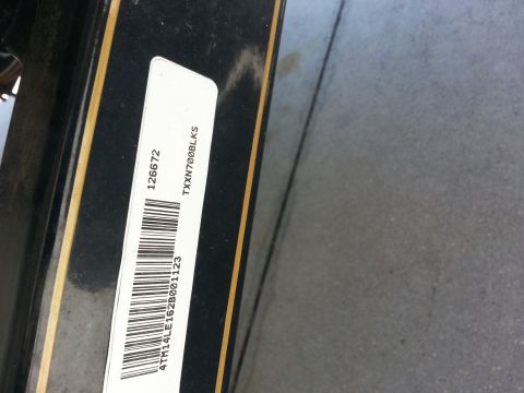 2003 Tracker Tournament - A white label with a barcode and alphanumeric text is affixed to a black surface with gold trim.