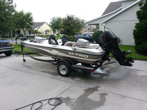 2003 Tracker Tournament - Bass boat with 'NITRO' branding is parked on a trailer in a residential driveway.