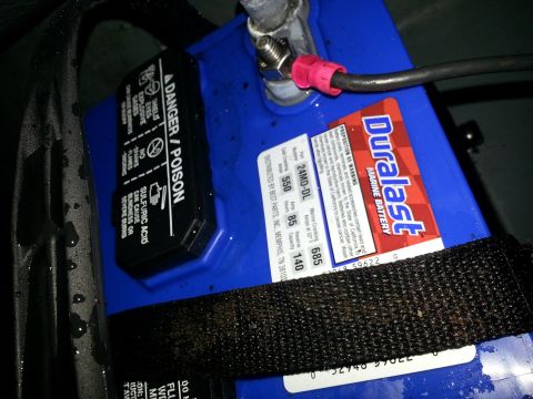 2003 Tracker Tournament - Close-up of a Duralast marine battery, showing warning labels and terminal connections.