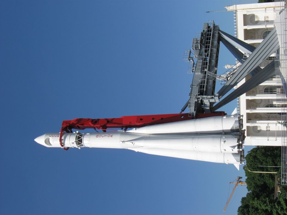 White rocket on launchpad with red arm against blue sky
