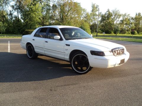 2000 Mercury Grand Marquis - A white 2000 Mercury Grand Marquis sedan is shown from a three-quarter front angle, aftermarket black wheels.