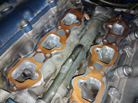 1995 Ford Probe - Close-up view of engine intake manifold gaskets, revealing wear and metal engine parts.