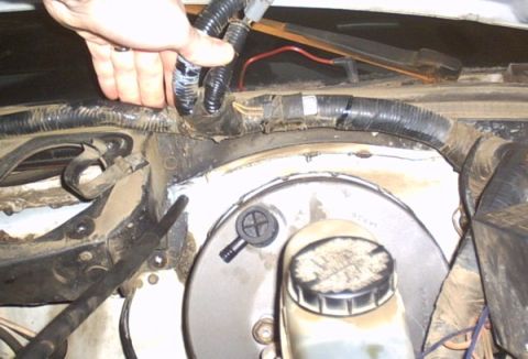 1991 Ford LTD Crown Victoria - Under-hood view at the firewall showing the round black brake booster with its translucent master cylinder reservoir and grimy cap, surroun…