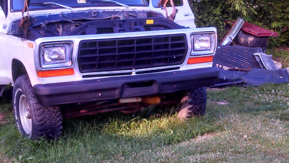 White 1979 Ford Bronco front end with hood open, parked on grass