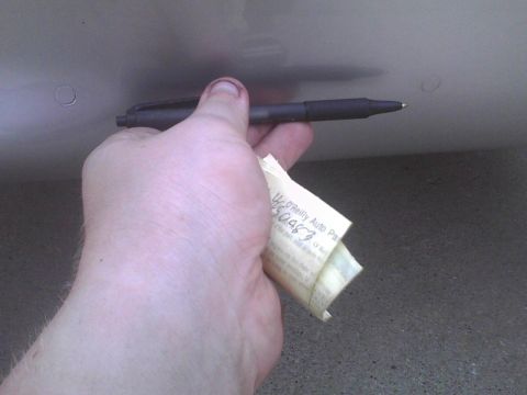 2003 Ford Crown Victoria - A hand holds a pen and a folded receipt from O'Reilly Auto Parts.