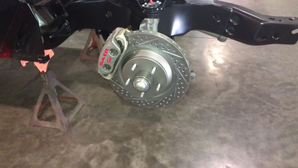 Car brake assembly with drilled rotor and Baer caliper, supported by jack stands