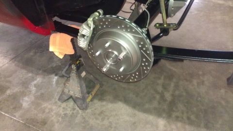 1972 Pontiac Trans Am - Close-up of a rear brake rotor and caliper assembly, with the vehicle supported by jack stands.