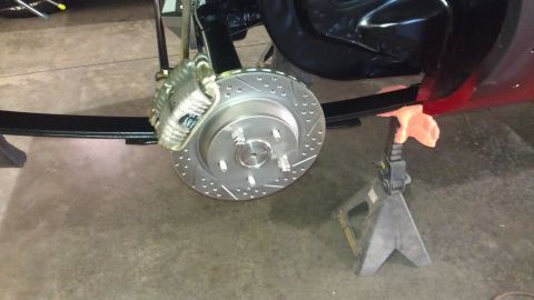 1972 Pontiac Trans Am - Close-up of a vehicle's rear brake assembly, including a drilled rotor and caliper, supported by jack stands.