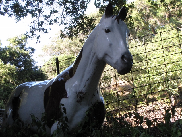 White and brown horse statue behind a fence