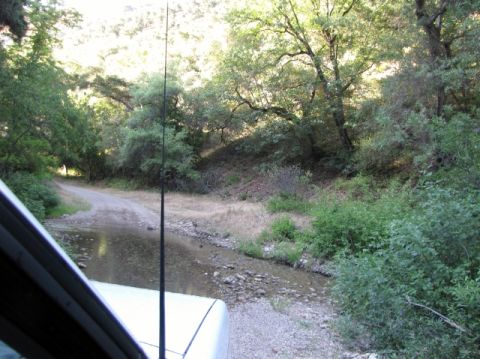 1992 Ford Explorer - The vehicle is navigating a water crossing on a dirt path through a wooded area.