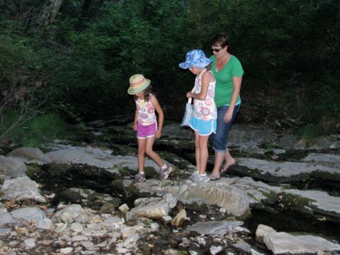 1992 Ford Explorer - A woman and two children navigate a rocky stream bed, surrounded by dense foliage.