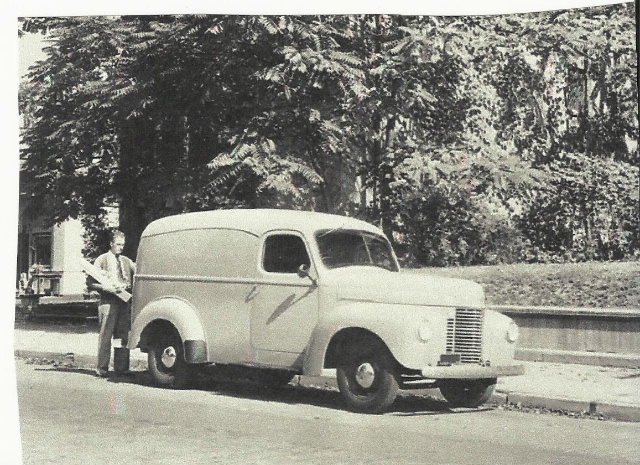 Vintage photo of a 1940s International panel truck parked curbside with a man standing beside it