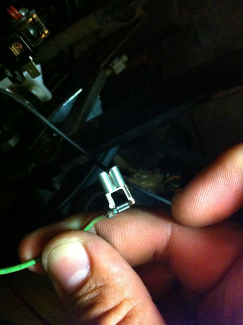 1995 Ford Mustang - Close-up of a hand holding a green wire with a metal connector, part of a vehicle's electrical system.