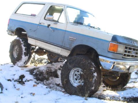 1988 Ford Bronco - This lifted 1988 Ford Bronco navigates snowy, off-road conditions with its prominent tires.