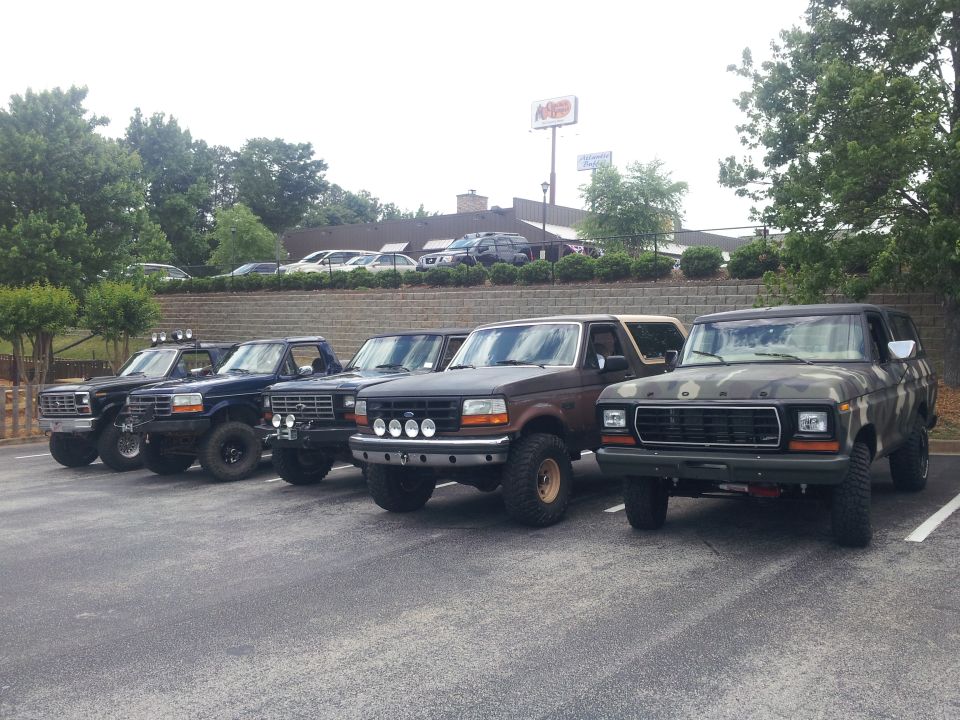 Five Ford Bronco SUVs parked in a lot, one with camouflage paint