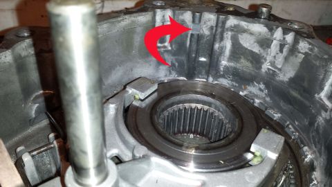 1987 Ford Bronco - A red arrow highlights a component within a disassembled transmission housing, revealing its internal workings.