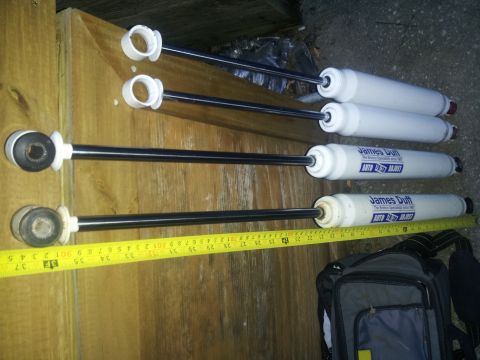 1988 Ford Bronco - Four James Duff shock absorbers are laid out with a measuring tape, indicating their size and specifications.